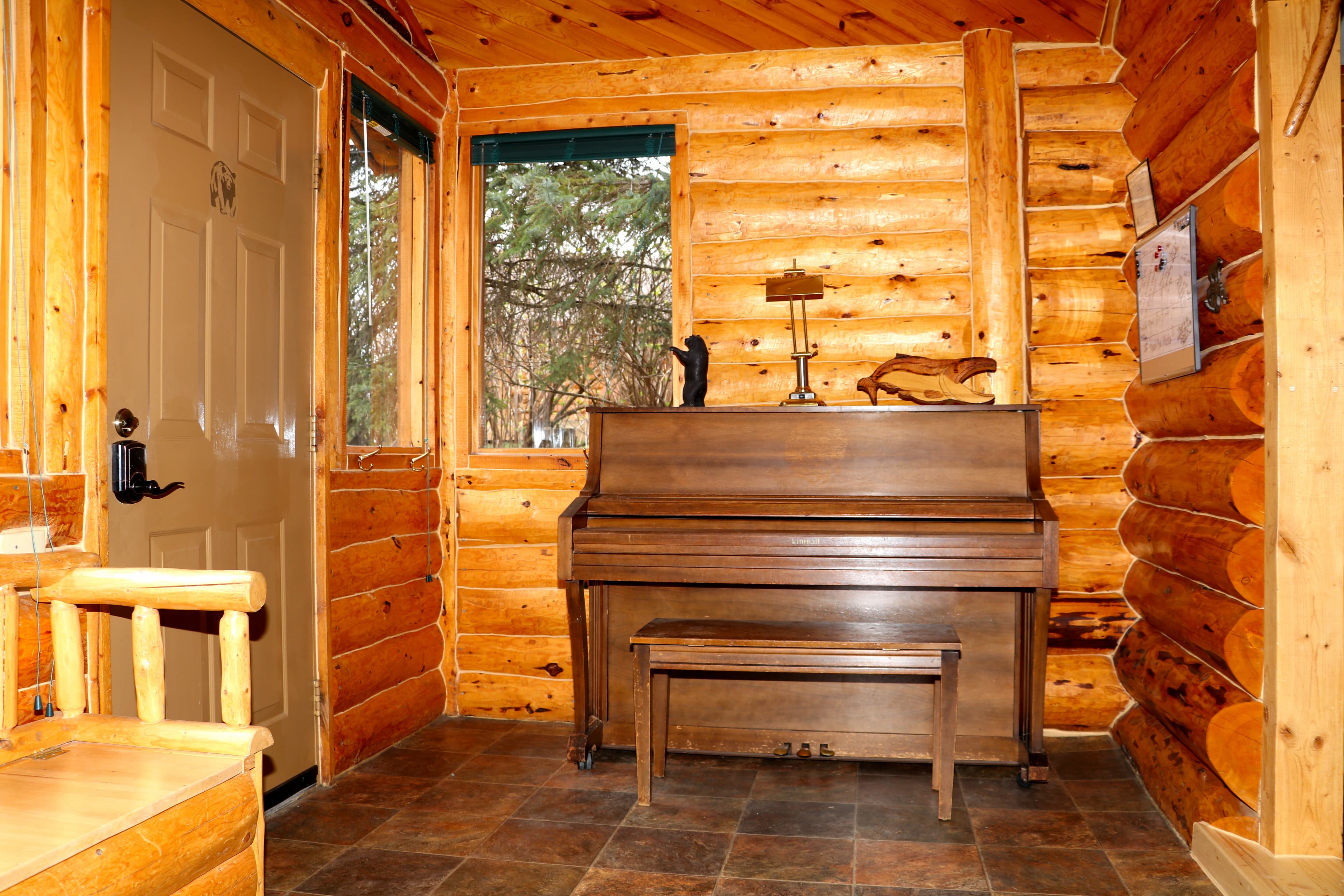 Entry room with log walls and piano with bench.