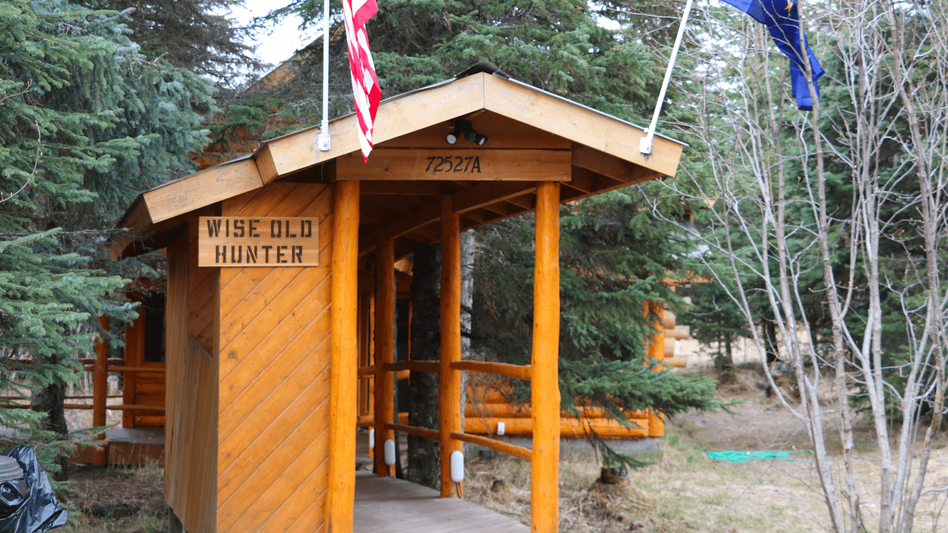 A wooden cabin entrance marked "Wise Old Hunter" surrounded by trees.